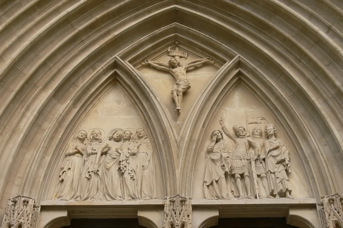 Il timpano scolpito del portale principale, con un Cristo crocifisso in alto e gruppi di figure in lutto in due archi a sesto acuto sottostanti.